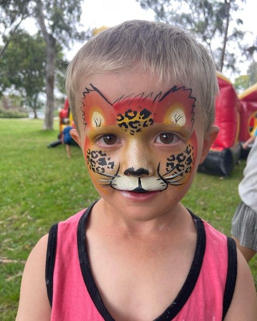 Tiger Face Painting Child displaying symmetrical tiger face paint outdoors