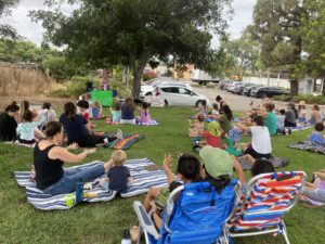 Sparkles performing for a seated family audience outdoors