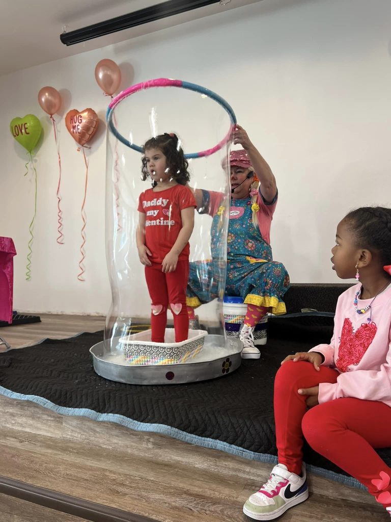 Child standing inside a giant bubble during Sparkles' bubble show