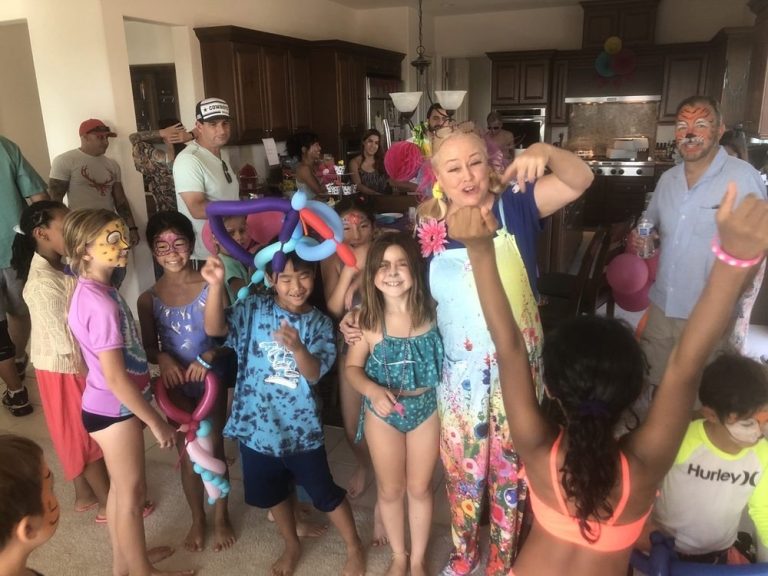 Sparkles leading a colorful group celebration with children and balloon creations