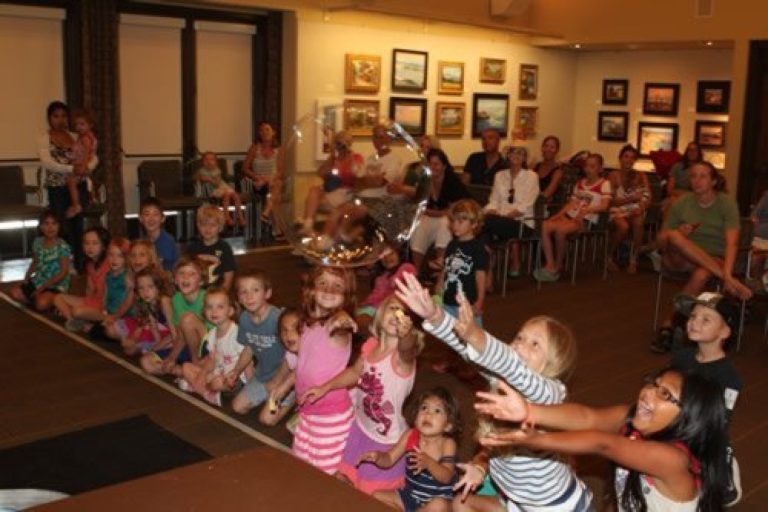 Children reaching toward Sparkles during an interactive indoor show