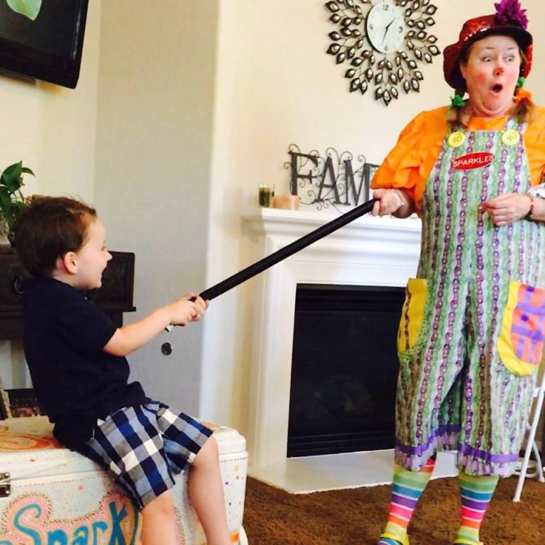 Sparkles reacting playfully as a child points a balloon sword during a magic show