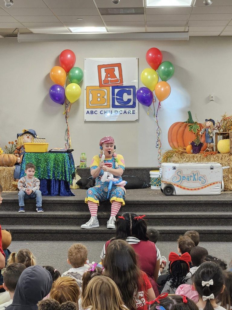 Sparkles performing onstage for children in a decorated library setting