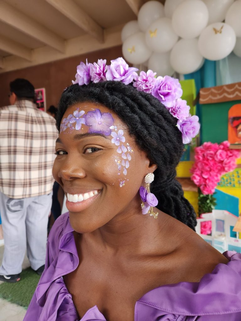 Guest smiling with purple floral face and body art