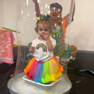 A child standing inside a giant bubble with Sparkles behind them